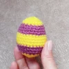 W dłoni Jajko z włóczki zrobione na szydełku wzorem w paski