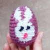 W dłoni Jajko z włóczki zrobione na szydełku wzorem z obrazkiem królika