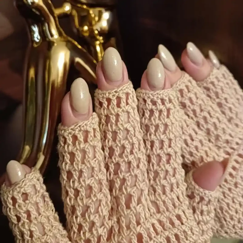 Dłonie w delikatnych szydełkowych rękawiczkach bawełnianych w kolorze beżowym.