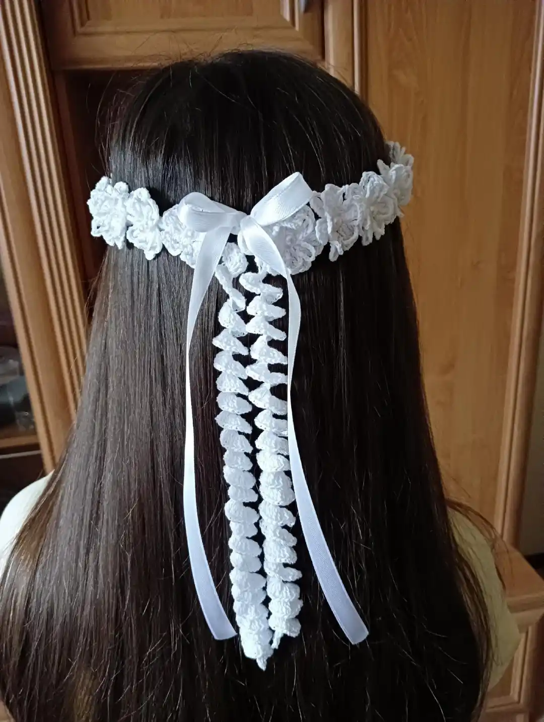 Wianek komunijny na głowie dziewczynki z długimi czarnymi włosami- widok z tyłu