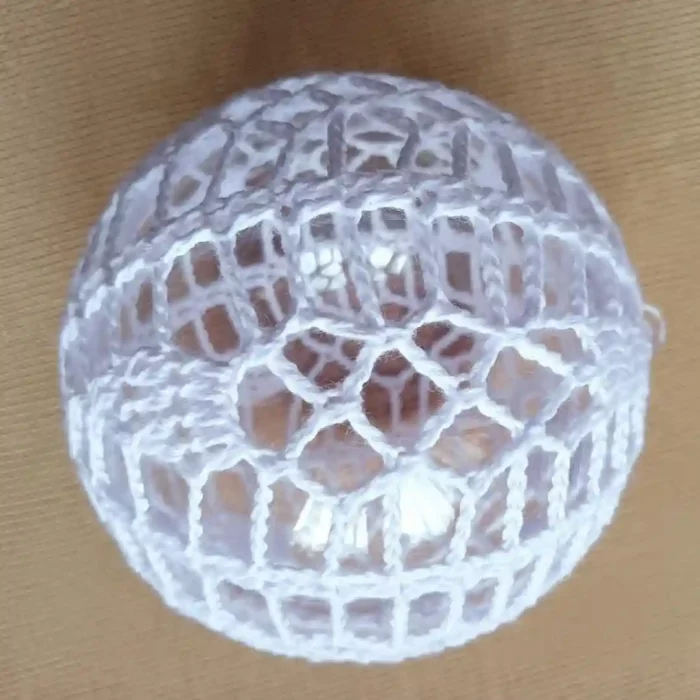 Bombka choinkowa zrobiona na szydełku na beżowym tle