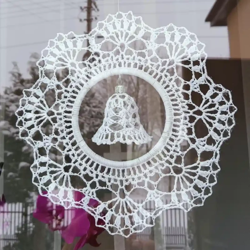 Na zdjęciu zawieszka z dzwoneczkiem zrobiona na szydełku, zawieszona w oknie