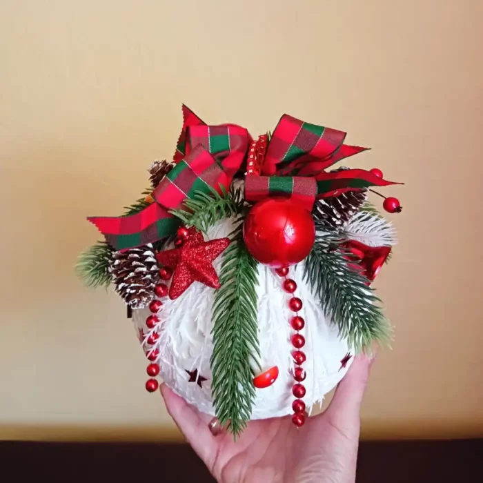 Duża bombka w kolorze białym ozdobiona świątecznymi dekoracjami