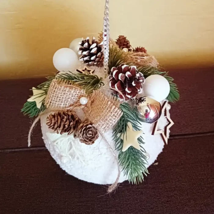 Duża bombka w kolorze białym ozdobiona świątecznymi dekoracjami