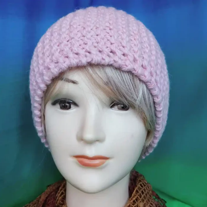 Ciepła czapka na zimę w kolorze pudrowego różu, prezentowana na głowie manekina damskiego