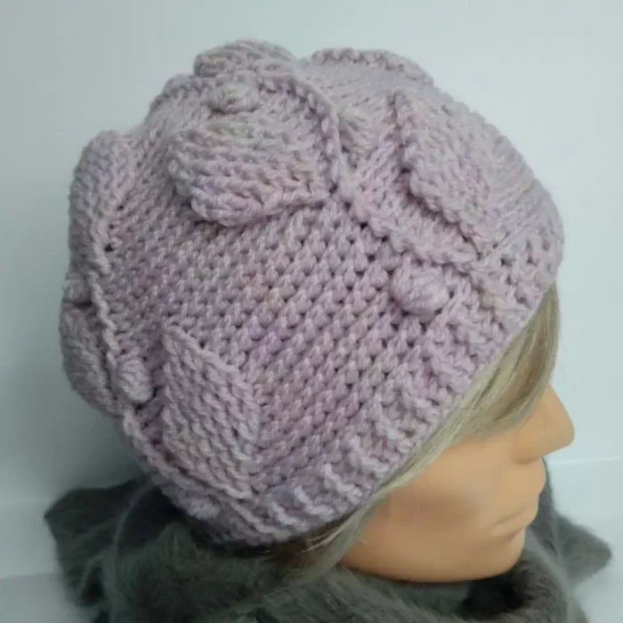 Czapka na szydełku z motywem listków w kolorze pudrowego różu prezentowana na głowie damskiego manekina.