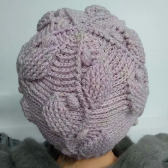 Czapka na szydełku z motywem listków w kolorze pudrowego różu prezentowana na głowie damskiego manekina. Widok czapki z tyłu głowy.