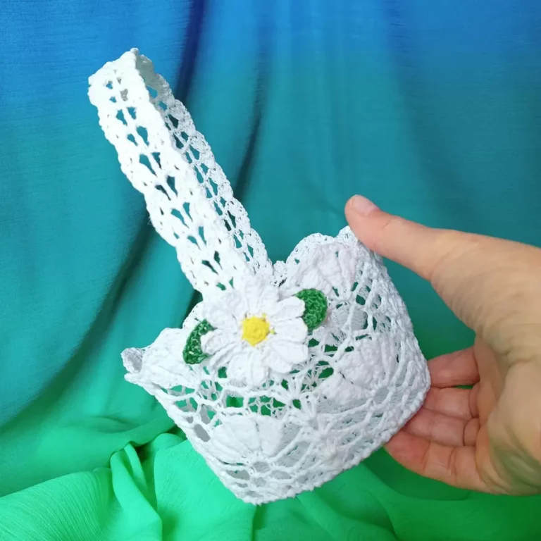 Dłoń trzymająca mały koszyczek zrobiony na szydełku z białego kordonka
