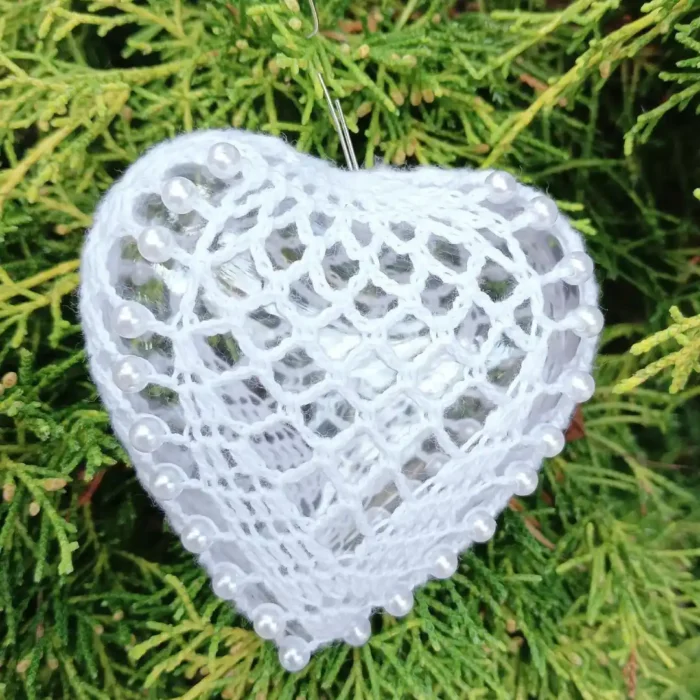 Serduszko na wypełnieniu akrylowym 8 cm z perełkami_5 Szydełkowe serce 8 cm zrobione z białego kordonka, z perelkami, na tle zielonego iglastego krzewu
