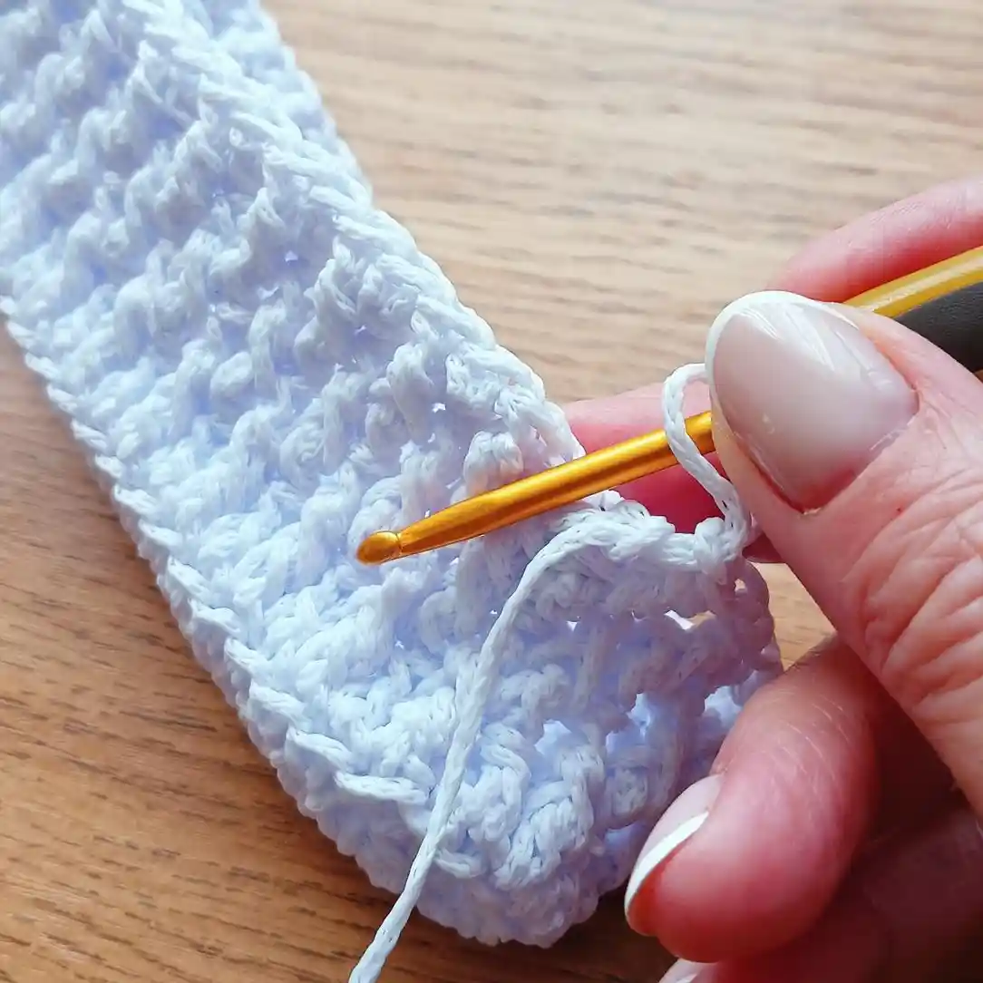 Dłoń trzymająca fragment robótki: torebka komunijna ze sznurka poliestrowego