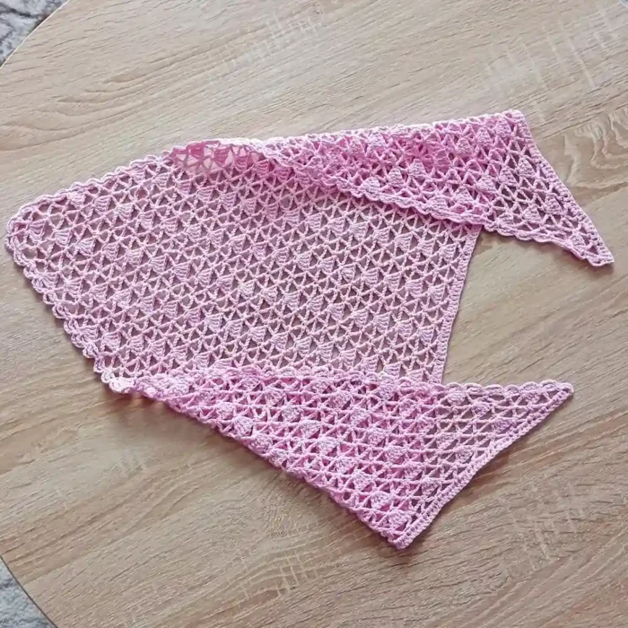 Chustka bandana zrobiona na szydełku_10 łożona różowa szydełkowa bandana na drewnianym stole.